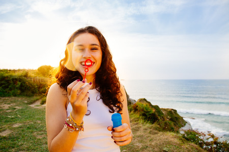 Funny young woman blowing bubbles over the sea at sunset. Sun flareの写真素材