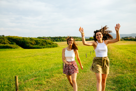 Funny female friends jumping in a green fieldの写真素材