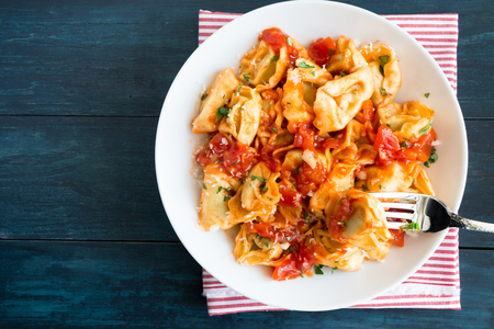 Fresh tortellini with homemade tomato sauce, chopped herbs and parmesan cheeseの写真素材
