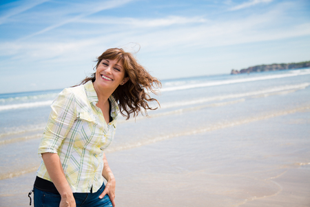 Happy middle aged woman enjoying the walk on the beachの写真素材