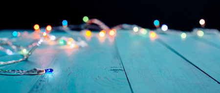 Colorful Christmas lights bokeh on blue wooden planks. Shallow depth of fieldの写真素材
