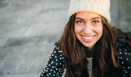 Cute and happy young woman with white woolen cap and lleather jacket smilingの写真素材
