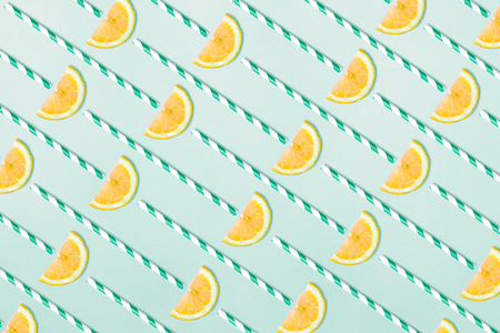 Pattern of lemon slices and straws on blue aquamarine background. Funny lemon juice concept