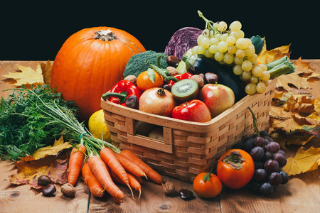 Assortment of fresh and ripe autumn vegetables and fruits on a rustic wooden table with black...