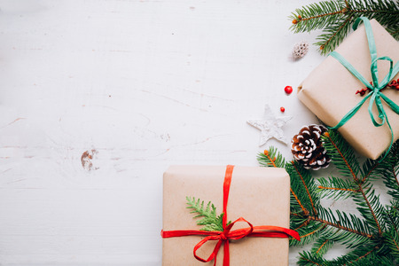 Christmas presents with paper craft, raffia bows, fir branches pin cones and  red berries on a white...