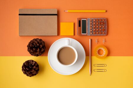 Office or school supplies with coffee cup and pine cones on an orange and yellow background. Flat lay. Back to office or school conceptの写真素材