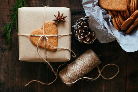 Rustic Christmas present with gingerbread heart cookie on a wooden tableの写真素材