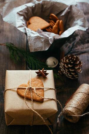 Rustic Christmas present with gingerbread heart cookie on a wooden tableの写真素材