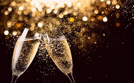 Two glasses of champagne toasting in the night with lights bokeh, glitter and sparks on the backgroundの写真素材