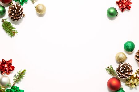 Christmas frame with red, green and golden  balls, bows, fir branches and pine cones isolated on whiteの写真素材