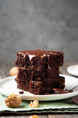 Chocolate spongy brownie cakes with walnuts and melted chocolate topping on a stackの写真素材