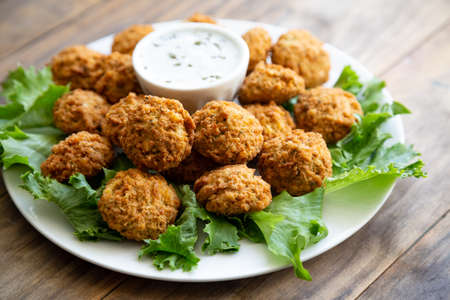 Homemade falafel with yogurt sauce on a rustic wooden table