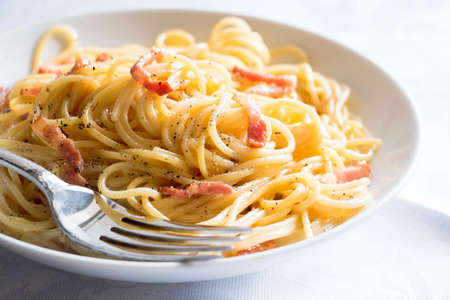 Traditional spaghetti carbonara with egg yolk, bacon, cheese and pepper