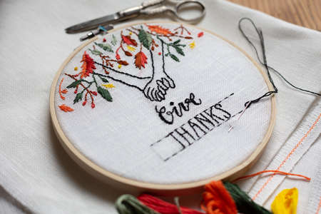 Embroidery hoop with a Thanksgiving embroidered illustration on a wooden tableの写真素材
