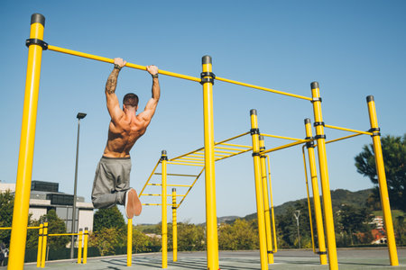 Young athletic man doing gymnastics on bars at a calisthenics gym outdoors