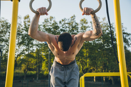 Athletic young man preparing and checking gymnastic rings before exercises at the calisthenics gym...
