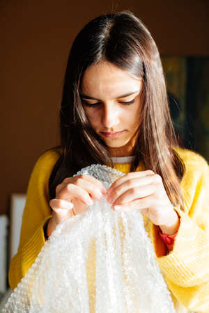 Teen girl popping bubbles in a  wrap at home to relax and fun