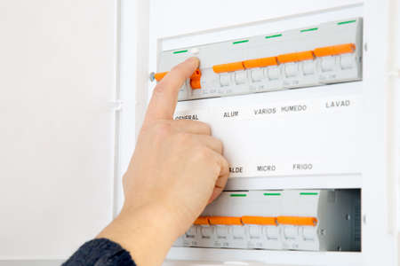 Woman hand switching off the fuse box at home. Words in spanish