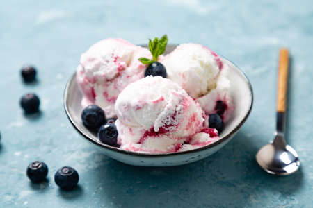 Homemade yogurt and blueberry ice cream with natural blueberry  in a bowl on a rough blue backgroundの写真素材