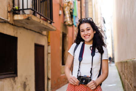 Young happy tourist woman walking down an european city alley with a vintage cameraの写真素材