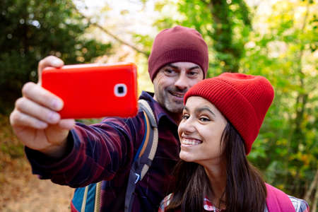 Happy father and teenage daughter taking a selfie and making funny faces during the journey in autumnの写真素材