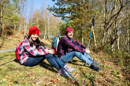 Happy father and teenage daughter sitting on the grass resting after the walk in the mountain in autumnの写真素材