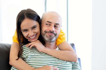 Happy teen girl with braces embracing her father who looks at her with funny faceの写真素材