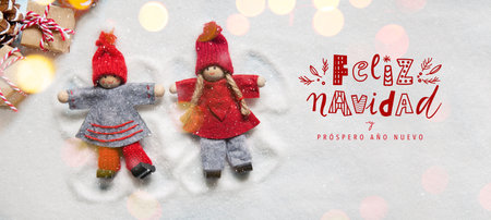 Christmas greeting card with little Christmas dolls ornaments making angels in the snow with lights bokeh. Funny handwriting letteringの写真素材