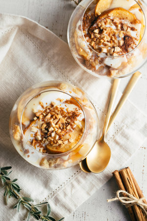 Christmas or autumn dessert in glasses made up of baked apple, crunchy almond cookies, custard, jam, yogurt, cinnamon, and toasted almonds. Parfait .Top viewの写真素材
