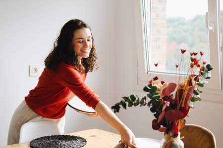 Young happy woman setting the table for dinner at homeの写真素材