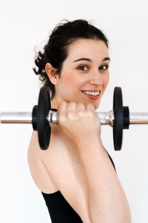 Young beautiful happy woman exercising at home with dumbbell to be fit