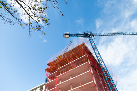 Apartment building under construction and cranes in a sunny day