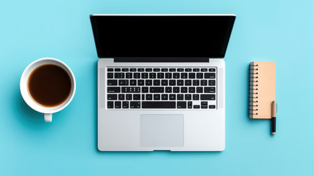 Top view of modern workplace with laptop computer, coffee cup and notebook on blue background.の素材