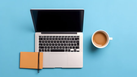 Laptop and coffee cup on blue background. Top view with copy spaceの素材