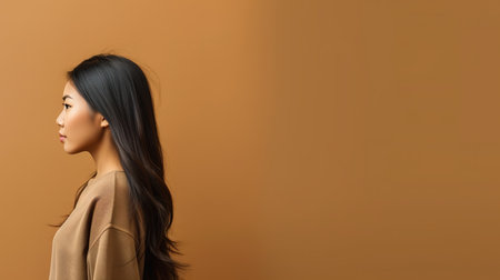 Portrait of a beautiful asian woman with long hair on brown backgroundの素材