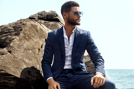Man in elegant suite posing in rock backgroundの写真素材