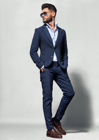 Elegant young handsome man in suite wearing glasses. Studio fashion portrait.の写真素材