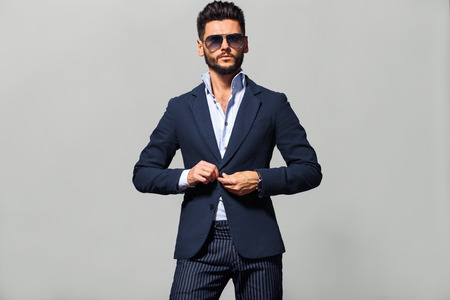 Elegant young handsome man in suite wearing glasses. Studio fashion portrait.の写真素材