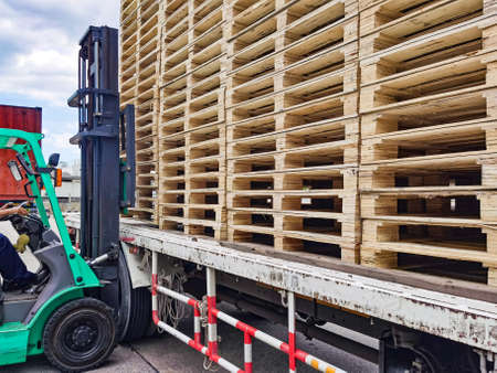 Worker driving forklift to loading and unloading wooden pallets from truck to warehouse cargo...