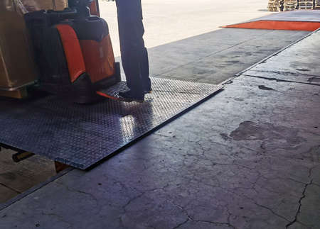 Worker driving forklift loading and unloading shipment carton boxes and goods on wooden pallet from container truck to warehouse cargo storage in logistics and transportation industrialの写真素材