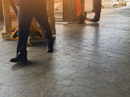 Worker driving forklift loading and unloading shipment carton boxes and goods on wooden pallet from container truck to warehouse cargo storage in logistics and transportation industrialの写真素材