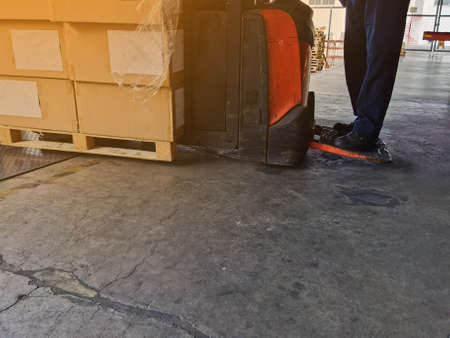 Worker driving forklift loading and unloading shipment carton boxes and goods on wooden pallet from...