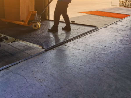 Worker driving forklift loading and unloading shipment carton boxes and goods on wooden pallet from container truck to warehouse cargo storage in logistics and transportation industrialの写真素材