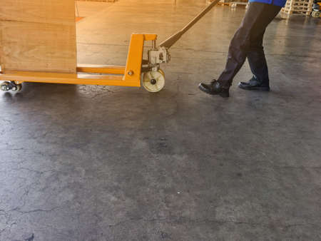 Worker driving forklift loading and unloading shipment carton boxes and goods on wooden pallet from...