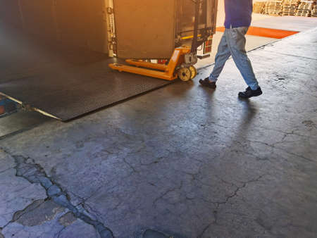 Worker driving forklift loading shipment carton boxes and goods on wooden pallet at loading dock...