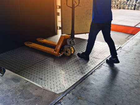 Worker driving forklift loading shipment carton boxes and goods on wooden pallet at loading dock...
