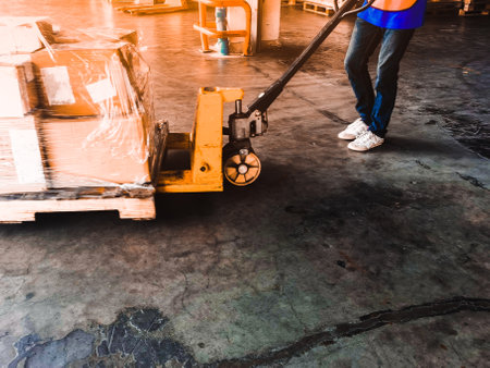 Worker driving forklift loading shipment carton boxes goods on wooden pallet at loading dock from container truck to warehouse cargo storage in freight logistics, transportation industrial, deliveryの写真素材