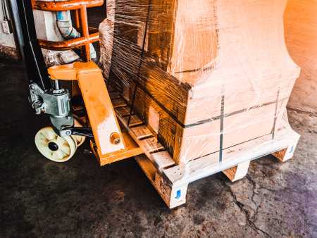 Worker driving forklift loading shipment carton boxes goods on wooden pallet at loading dock from container truck to warehouse cargo storage in freight logistics, transportation industrial, deliveryの写真素材