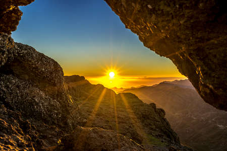 Sunset and mountain landscape view from eroded stone arch know as Ventana del nublo or La Agujereada. One of the higest places in Gran Canaria Island.の写真素材