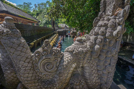 Bali, Indonesia - Sept. 9, 2017. Guardian Sculpture and Worshippers during purification ceremony at Pura Tirta Empul temple Holy Spring Watersのeditorial素材